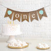 A burlap banner with letters reading &quot;one&quot; with images of white and mint striped hot air balloons on each side of the word.