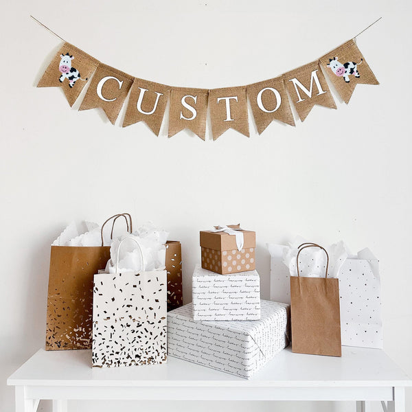 This personalized cow banner is the perfect addition to a farm themed baby shower or birthday celebration. The first flag features a smiling cow, you can add a name, date or saying with our burlap lettering, the banner ends with another cow flag.