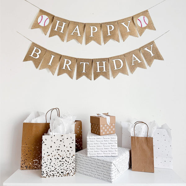 This Happy Birthday burlap banner runs on two lines. The top line starts with a hand stenciled baseball following back fishtail burlap flags spelling out the word happy. At the end of Happy, there is another baseball image. The second line spells out the word Birthday also in white lettering.