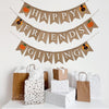 A burlap banner made from 4.5 by 6.5 inch fishtail shaped flags on 3 strings. The top line says HAPPY in white capital letters with a hand stenciled pumpkin and a hand stenciled turkey on each end. The middle string says FRIENDS with a turkey and a pumpkin on each end. The bottom string says GIVING with a pumpkin and a turkey on each end.