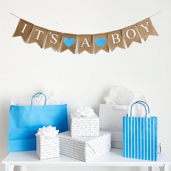 An It’s a Boy burlap banner strung on one string. Hand painted blue hearts are between the word it’s and a, and then between the words a and boy.