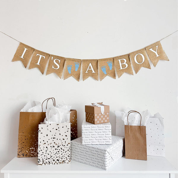 A burlap banner reading ITS A BOY with a blue baby footprint image flag between the words.