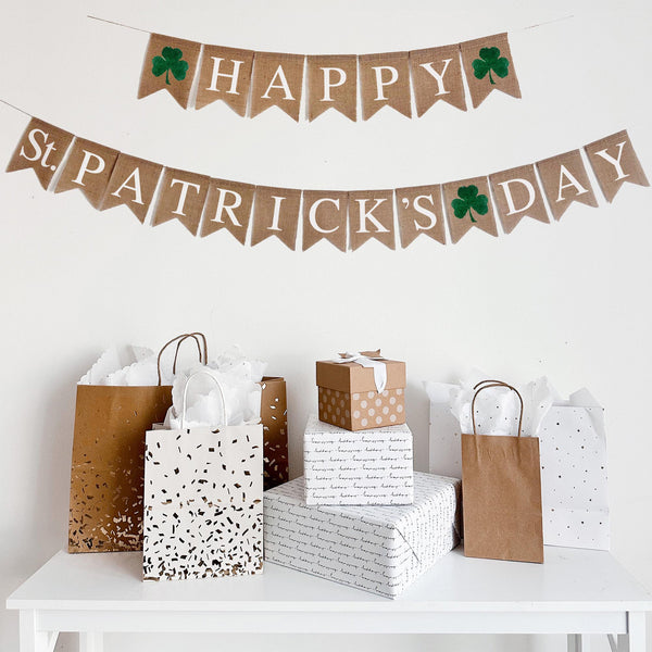 This Happy St. Patrick&#39;s Day Burlap Banner is the perfect rustic addition to your festive St. Patrick&#39;s Day celebration. The first line of this burlap banner starts with a green shamrock then reads Happy with a shamrock at the end. The second line reads St. Patrick&#39;s Day with a shamrock between the two words. The letters are white on a beige burlap background.