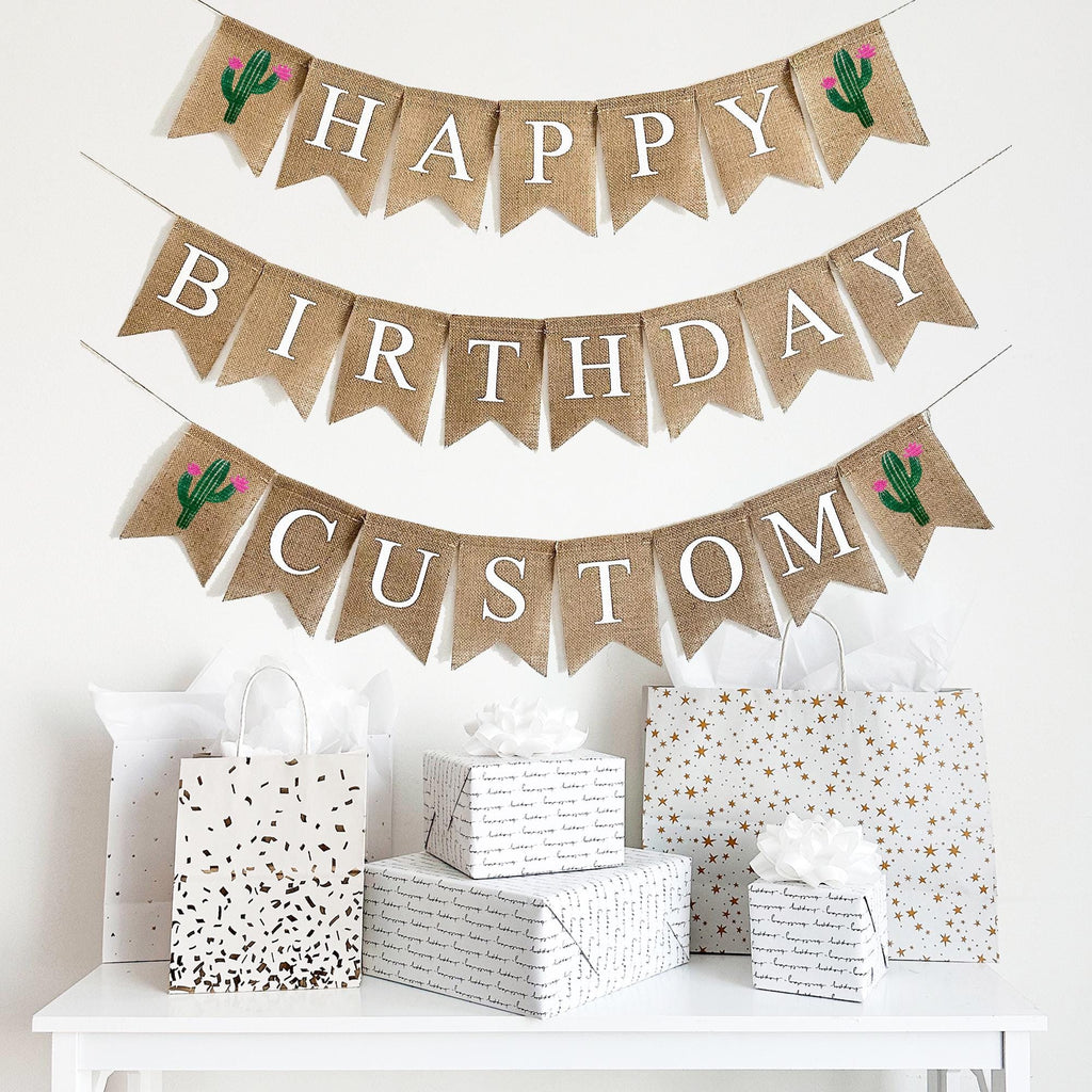 A happy birthday burlap banner strung on two or three strings. The top row reads &quot;HAPPY&quot; with a hand painted green cactus with pink flowers on each end of the word. The second line reads &quot;BIRTHDAY&quot;.  The third optional line give your the choice to add a personalization to your banner.  The personalized line also has a cactus with pink flowers on either end of the wording of your choice.