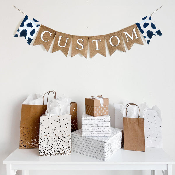 This personalized cow print banner is the perfect addition to a farm themed baby shower or birthday celebration. The first flag features a cow print fabric, you can add a name, date or saying with our burlap lettering, the banner ends with another cow print flag.