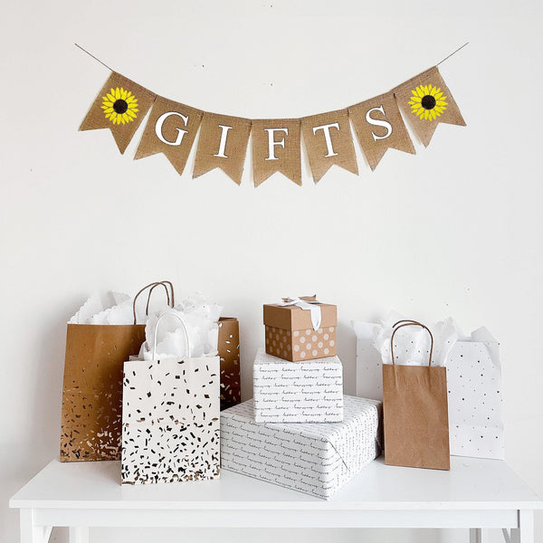 A burlap banner that reads &quot;Gifts&quot; with a hand stenciled sunflower on each end of the word.