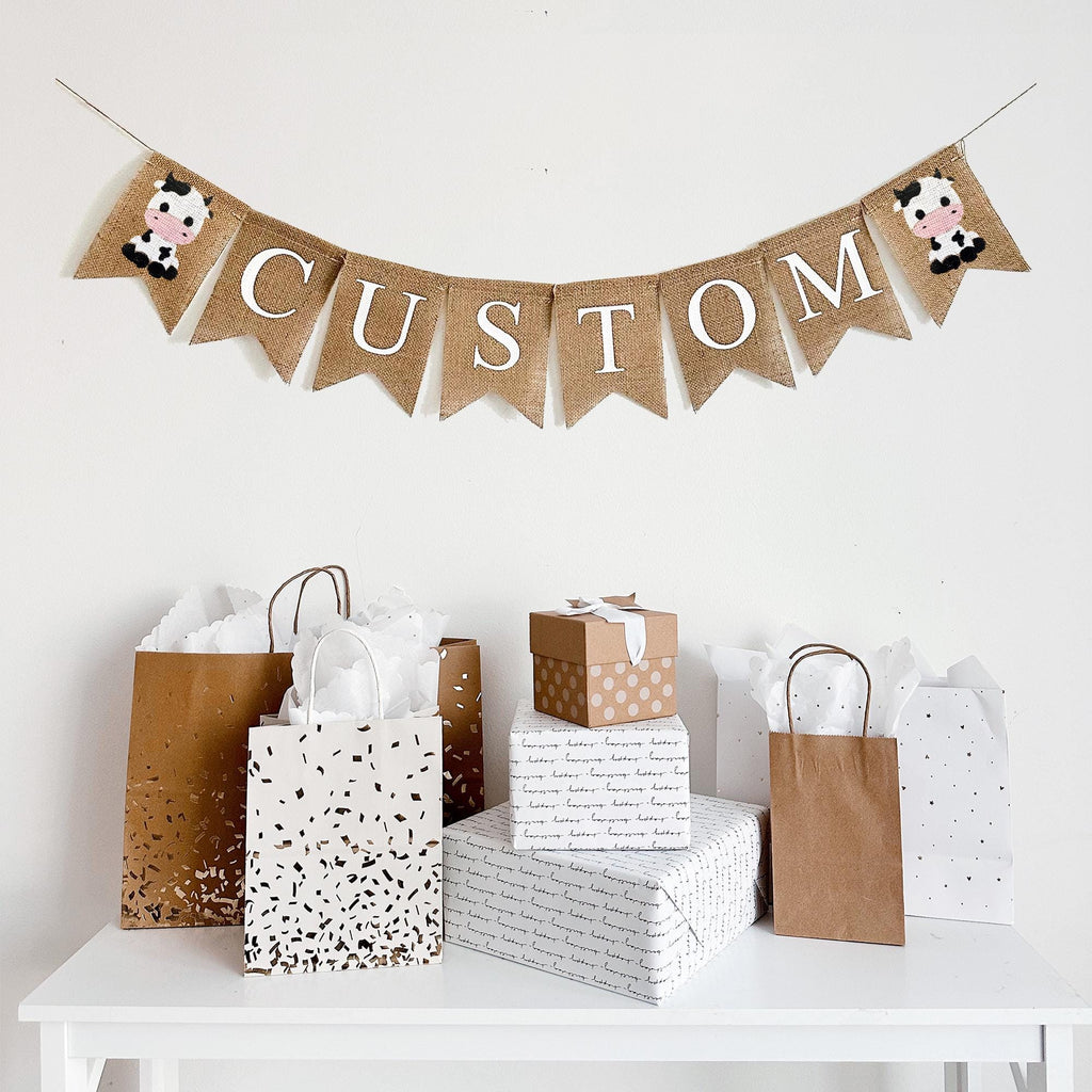 This personalized cow banner is the perfect addition to a farm themed baby shower or birthday celebration. The first flag features a smiling cow, you can add a name, date or saying with our burlap lettering, the banner ends with another cow flag.
