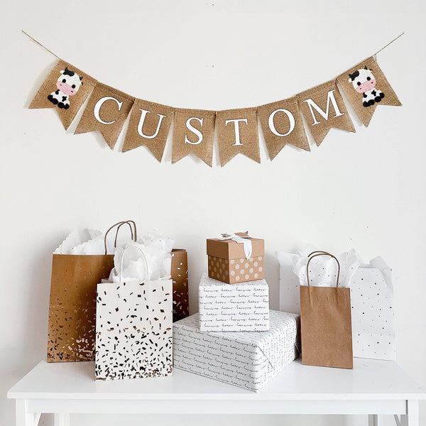 This personalized cow banner is the perfect addition to a farm themed baby shower or birthday celebration. The first flag features a smiling cow, you can add a name, date or saying with our burlap lettering, the banner ends with another cow flag.
