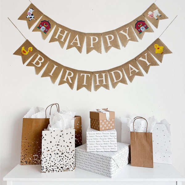 This Barn Themed Happy Birthday Banner is on two lines. The first line starts with a hand stenciled cow design followed by a detailed red barn. The flags then spell out the word Happy followed by another red bard and a sheep. The second line starts with a yellow duck followed by the word Birthday and ends with a yellow chick. With the inclusion of all of these barn inspired designed on this burlap banner, it&#39;s the perfect addition to any farm themed party.