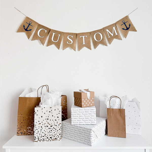 Anchors Aweigh! This custom banner features two hand stenciled navy blue anchors on either side of a customizable banner. Add a date, name or phrase to make your event extra special!