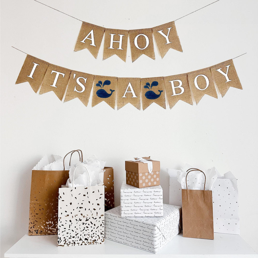 This Ahoy It&#39;s A Boy burlap banner is on two lines, with white letters painted on fishtail burlap flags. The first line reads Ahoy, the second line reads It&#39;s A Boy with a navy blue hand stenciled whale flag between each word.