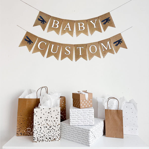 This customizable airplane themed burlap banner has two rows. The first row says Baby with a navy blue hand stenciled airplane on either side of the word. On the second line, you have two airplane on either end surrounding your choice of custom wording. Add a date, name or phrase to customize your celebration and creating long lasting memories.