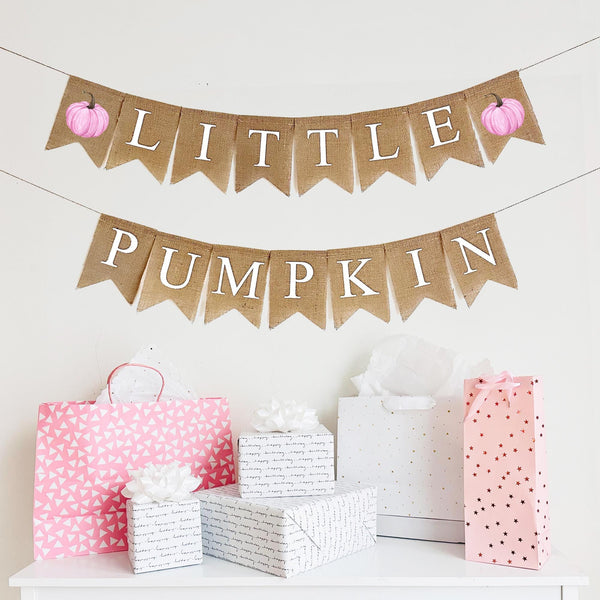 Burlap banner with two layers includes two  pink watercolor pumpkins. The letters on the banner spell out Little Pumpkin in white traditional font.