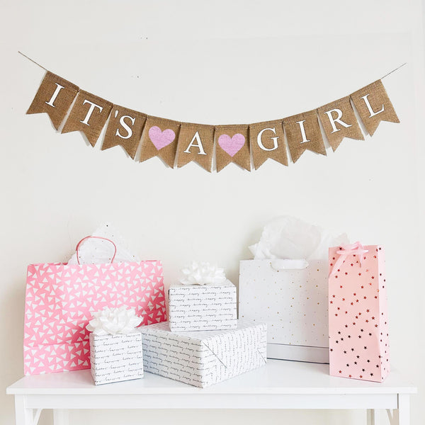 An It’s a Girl burlap banner strung on one string. Hand painted pink hearts are between the word it’s and a, and then between the words a and girl.