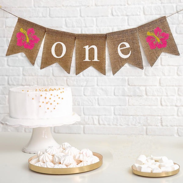 First Birthday Burlap Banner. With pink and yellow hibiscus flowers on either end of the banner, the letters spell out o n e in white on burlap flags.