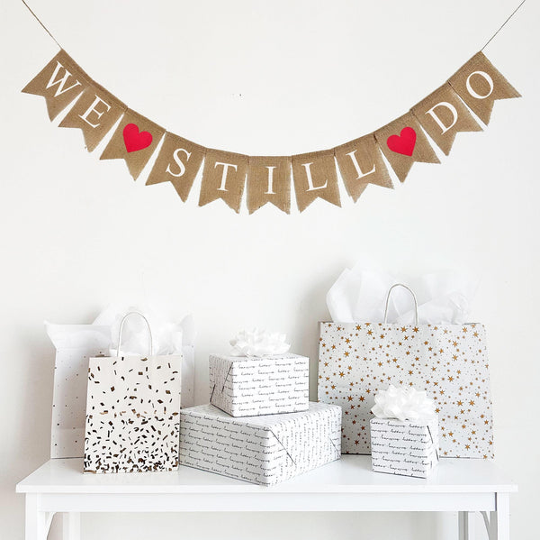 A burlap banner that says We Still Do with red hearts between the words.