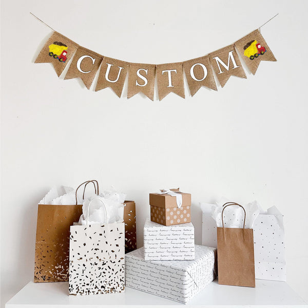 Customize this construction burlap banner with the wording of your choice. Each burlap flag measures 4.5 x 6.5 inches. On either end of the personalized wording, this banner comes with two hand stenciled yellow and red dump trucks.