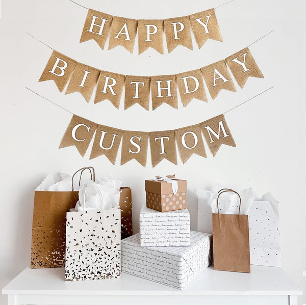 A three tiered burlap banner. The first tier reads happy, second tier reads birthday, and third tier reads custom- you can add the name of your choice or order just Happy Birthday. The lettering is all white capital letters.