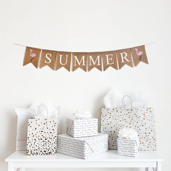 Summer Burlap Banner. Summer is written in white lettering on burlap flags with a hand stenciled bright pink flamingo image flag on each end of the word.
