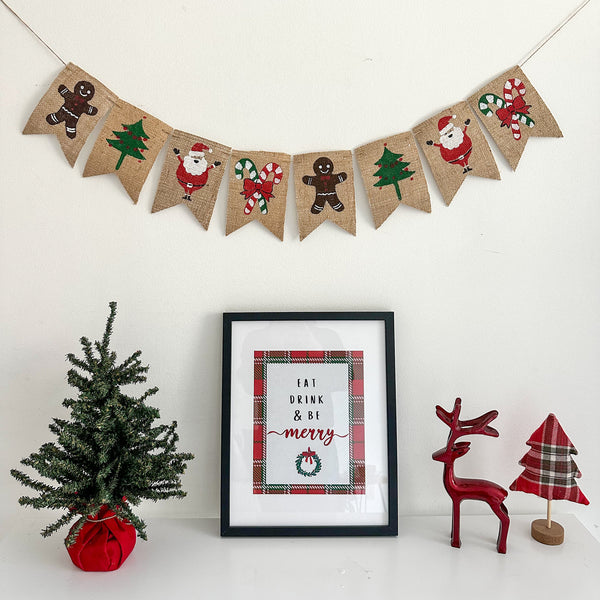 A burlap banner with two gingerbread men, two Christmas trees, 2 Santa Claus, & two candy cane images painted onto 4x6 burlap flags.
